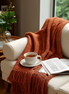Chunky knit tassel throw over a sofa arm with tea and a magazine