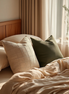 Textured cushion covers in coffee and dark green on a linen bed, morning light