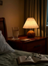The Nami pleated bedside lamp on a nightstand late at night