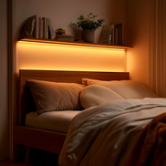 Warm LED strip glowing under a floating shelf above a bed at dusk