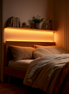 Warm LED strip glowing under a floating shelf above a bed at dusk