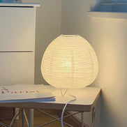 The Haru rice paper table lamp glowing warm on a white side table in a quiet corner