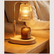 The Ember Lamp warming a jar candle on a wood side table